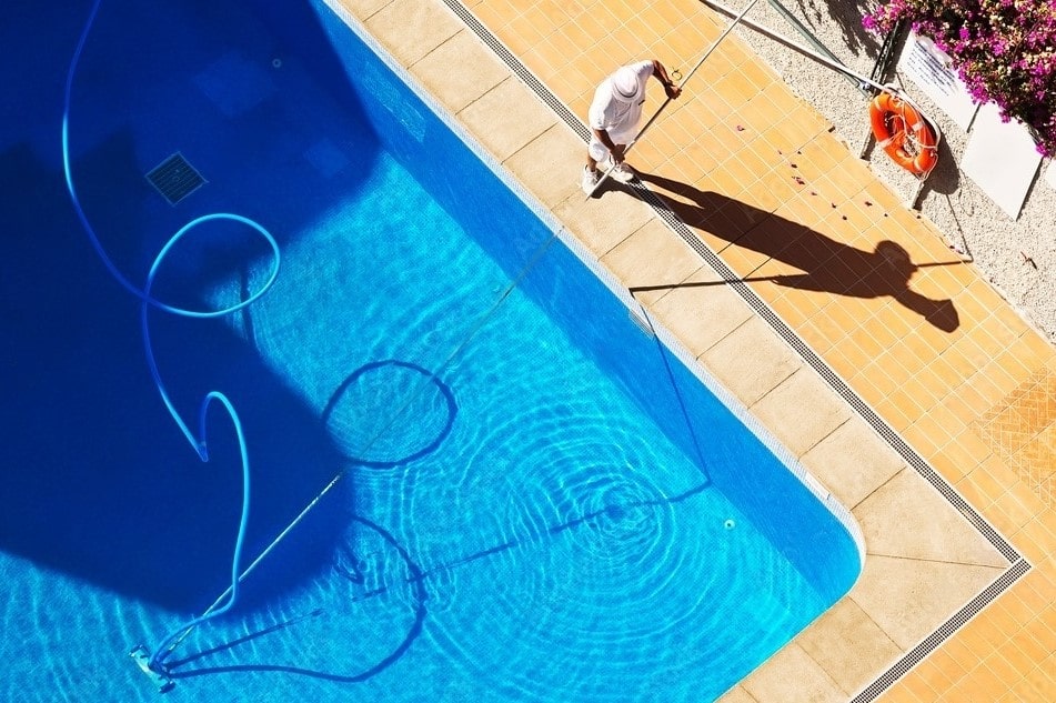 Contracteur professionnel entretenant et nettoyant une piscine creusée bleue